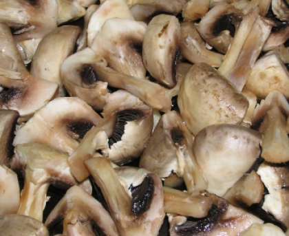 Затем возьмите грибы, лучше свежие шампиньоны. Почистите их и вымойте. Обсушенные грибы поделите на четыре части.