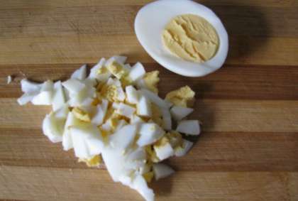 Потом отварите яйца в кипящей воде до десяти минут. Готовые яйца вытяните и положите в миску с холодной водой, - это для того, чтобы, когда будете чистить яйцо, вы не повредили белок. Потом очистите их и нашинкуйте мелкими кусочками.