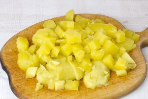 Картофель помойте. Приготовьте воду в кастрюле. Потом отварите клубни картофеля в «мундирах» до готовности. Охладите. Очистите картофель и после этого тонко нарежьте соломкой или ломтиками.