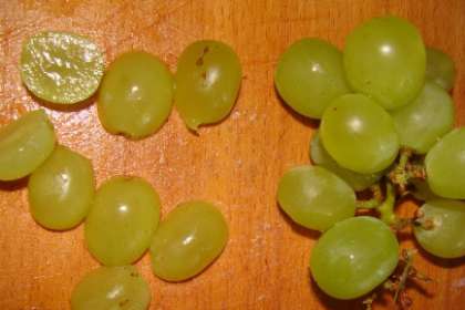 Помойте виноградную гроздью Отделите виноградинки от деревянных веточек. После этого разрежьте каждую виноградинку надвое. Если есть косточки в винограде, удалите их.