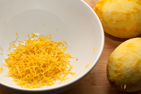 Лимоны вымойте, подержите в кипятке 2-3 минуты, затем снимите цедру (только самую верхнюю желтую часть) с помощью мелкой терки. Из половины одного лимона выжмите сок.