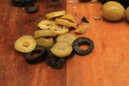 Оливки вытащить ложечкой из банки. Часть из них порезать колечками, а часть оставить как украшение для салата.