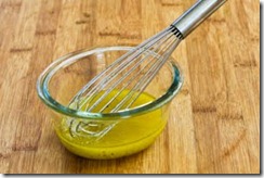 Приготовьте заправку в отдельной посуде. Налейте масла (растительного, подсолнечного, можно оливкового), уксуса. Затем положите сахар, соль, насыпьте красного перца. Взбейте смесь венчиком.