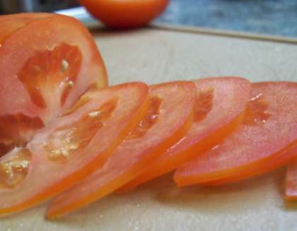 Возьмите помидоры, сначала помойте, а потом обсушите их. После этого следует порезать их на кружочки. Если они слишком мясистые, то мякоть нужно вырезать, а то салат потечет.