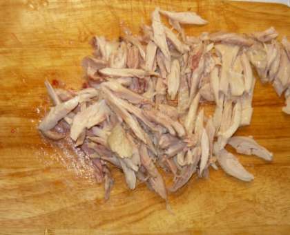 Сварите курицу до готовности. Немного посолите воду во время варки. Потом разделайте тушку (отделите мясо от кости, удалите шкуру). Мясо вареной курицы порежьте соломкой. Можно разобрать на волокна руками.
