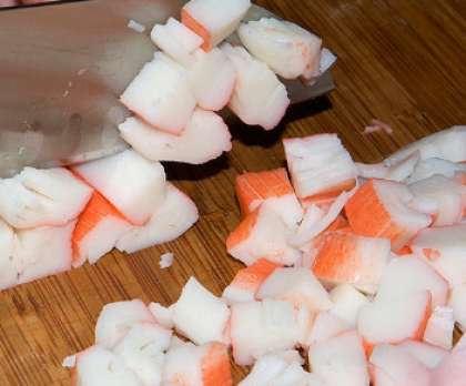 Крабовые палочки выньте из упаковки. Лучше, когда они будут охлажденными, а не замороженными. Порежьте затем палочки кубиками либо потрите на большую терку. Можно также использовать для этого блюда крабовое мясо.