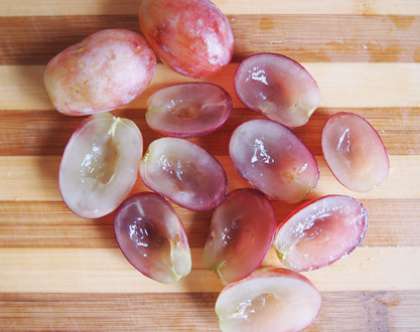 Вымойте затем гроздь винограда. Просушите. Возьмите и отделите плодоножку от ягод. Каждую виноградинку разрежьте потом пополам.