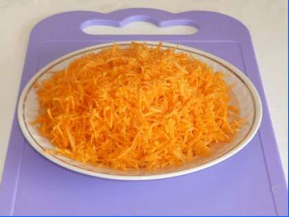 Сырую морковь почистите. Вымойте и просушите. Потом возьмите терку и мелко натрите плоды моркови.