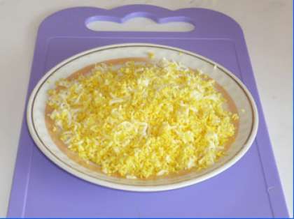 Сварите яйца. Охладите, затем почистите их. Оставьте 1-2 желтка на украшение блюда, остальные яйца потрите мелко на терке.