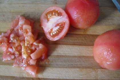Помойте помидоры. Ошпарьте их кипятком, а потом снимите с них кожуру. Потом возьмите и разрежьте их на половину. Вилкой придавите, чтобы выдавить немного лишнего сока. Разрежьте помидоры на средние кусочки.