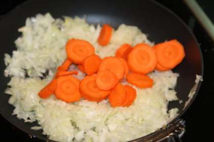 Тем временем нужно измельчить лук и нарезать кольцами морковь. Обжарить на сковороде с добавлением оливкового масла до золотистого цвета. Жарить овощи на небольшом огне, чтобы лук не пережарился.