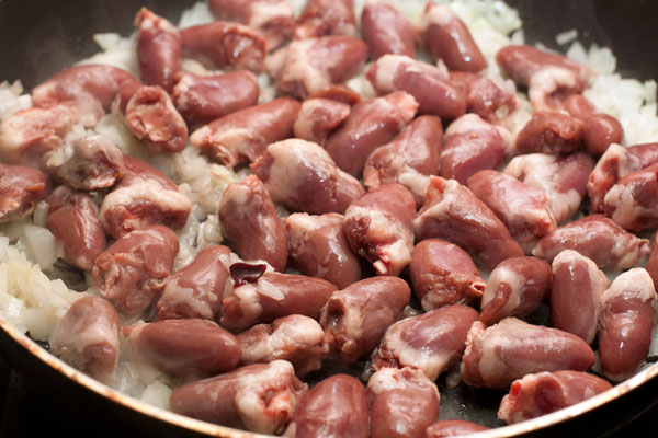 Куриные сердечки промойте в холодной воде, срежьте лишний жир и сосуды (если есть) и положите в сковороду.   Готовьте на среднем огне, помешивая, пока сердечки не утратят розовый оттенок.