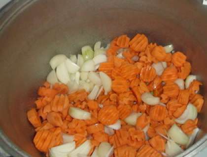 В кастрюлю глубокую, объемом почти 8 литров. Влейте в нее растительное масло. Положите потом лук и порезанную морковь. Включите мелкий огонь и поставьте салат на плиту. Пассируйте, пока овощи не станут мягкими. Не зажаривайте их!