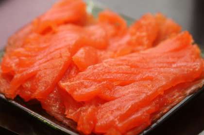 Возьмите семгу. Порежьте рыбу на тонкие ломтики. На блюдо с зеленью и редисом положите слой порезанной семги. Вместо семги можно также использовать форель либо горбушу.