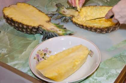 Возьмите нож и надрежьте мякоть ананаса. Аккуратно достаньте ее из плода. Старайтесь не повредить само основание обеих половинок. Отложите их в сторону – это будут наши «салатницы».