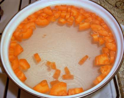 Прежде всего, нужно подготовить все необходимые ингредиенты. Одну крупную морковь нужно очистить и нарубить мелко квадратиками. Поставить на огонь кастрюлю с двумя литрами воды, довести до кипения и бросить нарезанную морковь. Варить до готовности.
