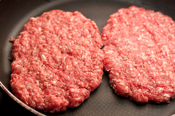 Хорошо разогрейте сковороду без масла (чугунную или с антипригарным покрытием) и положите на нее гамбургеры.