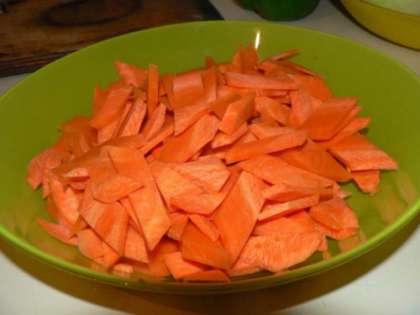 Для приготовления этого блюда нужно подготовить, прежде всего, овощи. Для этого мы шинкуем морковь в виде ромбиков или соломки. Затем очищаем и моем крупную луковицу, нарезаем ее дольками, словно режем яблоки. В этом блюде очень важно, чтобы овощи были крупно нарезаны и при тушении не превратились в кашу. Можно добавить любые овощи на ваш вкус, главное, чтобы они не имели ярко выраженный острый вкус или слишком сладкий, например, как у свеклы. Далее мы рвем на крупные куски болгарский перец. В данном случае мы используем зеленый перец, но можно также взять пару сладких перцев. Получится очень веселая и яркая палитра и сочный сладкий вкус перцев дополнит блюдо. Тем временем займемся чесноком. Чтобы чеснок не давал характерную горечь и остроту, нужно удалить с каждой дольки сердцевину. Затем мелко порубить чеснок и отложить в сторону.