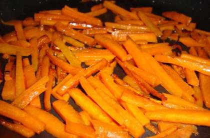 Затем нужно нарезать морковь соломкой и обжарить до золотистого цвета на сковороде с добавлением двух столовых ложек растительного масла. При желании можно обжарить вместе с морковью томаты, болгарский перец или кабачок. Тушить нужно до появления золотистого цвета и состояния вялости овощей. Как только морковь обжарится, огонь нужно уменьшить. Чеснок мелко нарезать и добавить к обжаренной моркови. Затем нужно добавить отварную фасоль, прежде слив с кастрюли воду. При необходимости можно добавить еще немного растительного масла и  тушить в течение 5-7 минут, постоянно помешивая. Нужно следить за тем, чтобы смесь не подгорела.