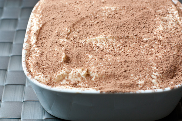На печенье выложите еще треть крема, затем еще раз уложите слой пропитанных бисквитов. Покройте их оставшимся кремом, разровняйте и густо посыпьте какао-порошком.   