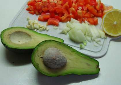 Спелое авокадо разрезать вдоль на половинки и вынуть большую косточку. Затем ложкой вынуть мякоть и положить ее в блендер к помидорам.