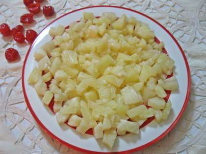 На блюдо выкладываем нарезанные кубиками ананасы, смазываем слой майонезом и сверху посыпаем натертым сыром.