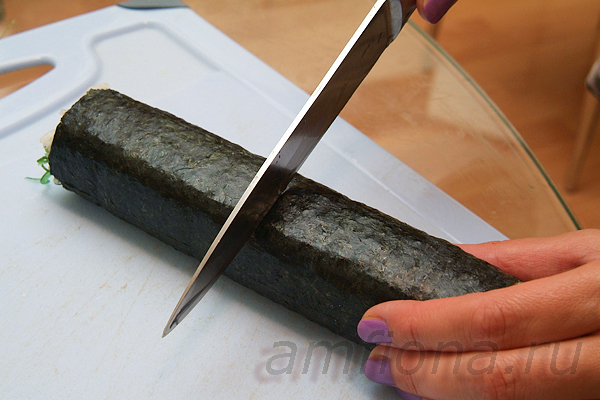 Перенесите ролл на разделочную доску, смочите лезвие ножа и разрежьте ролл на две половинки.