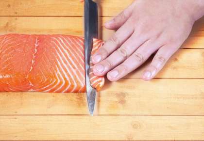 Отрезаем небольшой кусок лосося, как раз такой, какой будет использоваться в суши – пластинка длиной около 8 см, шириной 1,5-2 см и толщиной примерно 0,5 см. А так как вы готовите суши дома, никто не запретит вам использовать ваши любимые размеры, ориентируясь только на свой вкус.