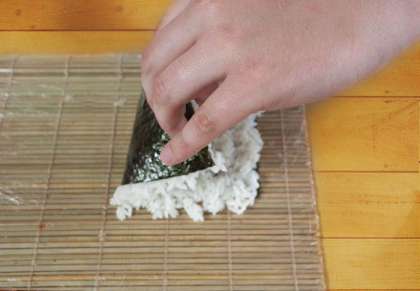 Аккуратно переворачиваем лист нори с рисом пополам
