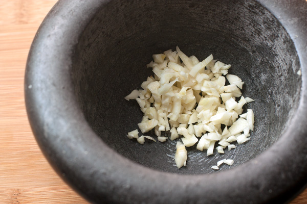 Мелко нарежьте чеснок, разотрите его в ступке с добавлением крупной соли, чтобы получилась кашица.  Добавьте измельченный или натертый на терке свежий имбирь и перец.