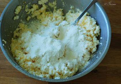 В посуде хорошенько смешаем масло, яйцо, соль и сахар. Затем добавим наш творог и как следует разомнём его, смешивая с яйцом. Присыплем 2-3 столовыми ложками муки.