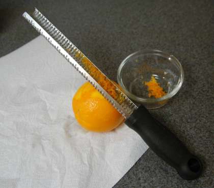 Натрите апельсиновую кожуру в миску.