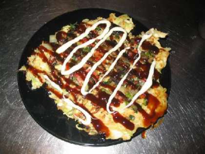 Выкладываем блюдо на широкую тарелку и щедро поливаем соусом Okonomiyaki и майонезом.