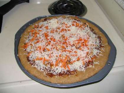 Выкладываем ингредиенты пиццы слоями на основу. Посыпаем сверху сыром.