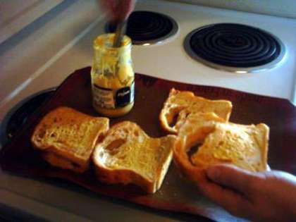 Нарезаем хлеб ножом с зубчатым лезвием. Можно использовать нож для стейка. Промазываем кусочки горчицей.