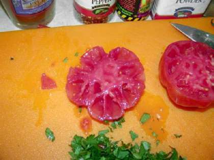 Промойте помидор горячей водой и поместите в холодную для того, чтобы удалить кожу. Порежьте помидор пополам.