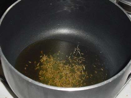 Ставим кастрюлю на средний огонь. Наливаем примерно 3 столовые ложки оливкового масла и посыпаем 2 чайными ложками тмина. Когда семена тмина начнут шипеть и потрескивать переходим к следующему шагу.