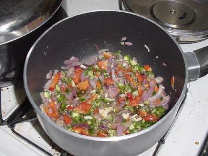 Далее добавляем чеснок, чили перец, красный перчик и другие остальные овощи которые вам необходимы в блюде. Помешиваем на среднем огне около 2 минут.