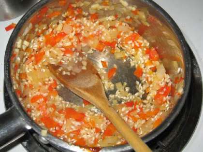 Поджарим перец, чеснок и лук-шалот в сковороде с оливковым маслом. Добавляем рис и мешаем в течении 3 минут.