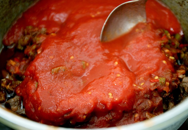 Консервированные томаты измельчаем и тоже заливаем в мясо.