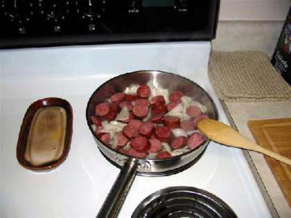 В нагретой сковороде смешиваем колбасу и лук.