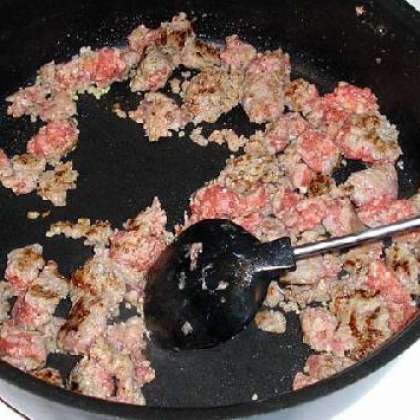 Когда колбаса поджарится наполовину, добавляем чеснок.