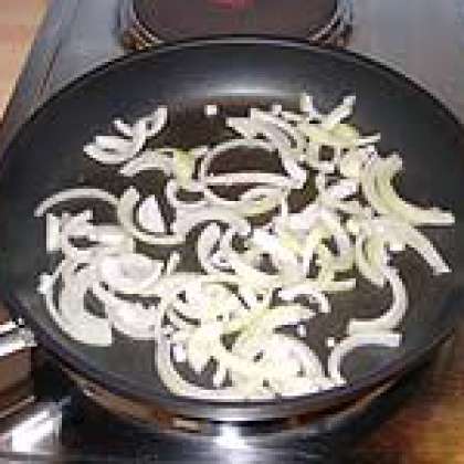 В разогретую сковороду влить масло. Нарезать лук половинками колец и обжаривать до прозрачности.