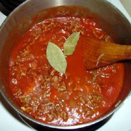 Поместите помидоры под горячую воду и удалите кожицу. Варите томатный соус на среднем огне в большой кастрюле. Добавляем готовый фарш в соус. Затем добавляем перец, помидоры и лавровый лист. Накрываем крышкой и готовим на среднем огне.