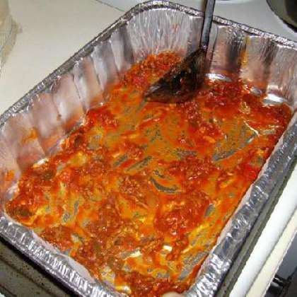 Налейте тонкий слой томатного соуса на дно посуды для выпечки.