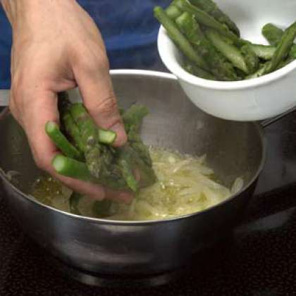 В большой кастрюле, влейте оливковое масло и добавьте нарезанный соломкой лук. Как только лук смягчился, добавьте головки спаржи, порежьте надвое продольно. Готовьте в течение приблизительно 2 - 3 минут и добавьте соль и перец. Дайте остыть.