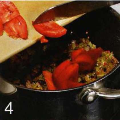 Выложить чесночно-луковую смесь в мясо. Засыпать муку и порошка чили. Перемешать. Влить 300 мл воды, добавить сладкий перец, томаты и томатную пасту.