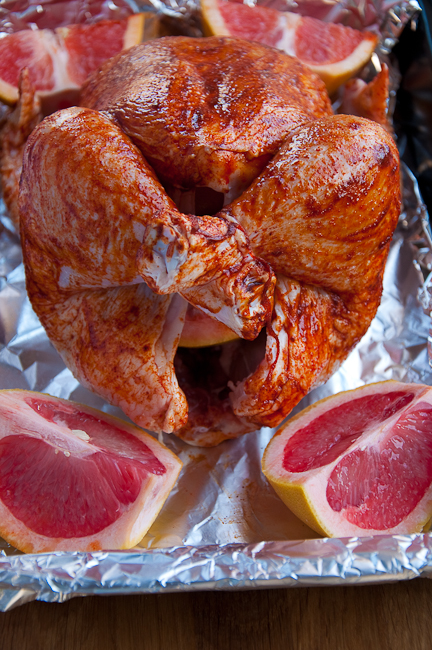 Паприку смешать с маслом и нанести на курицу, посолить. Грейпфрут разрезать на 4 части, начинить им курицу (сколько в нее поместится), остальной положить рядом за полчаса до конца запекания.    Запекать при 170 градусах - из расчета 50 минут на килограмм курицы.    