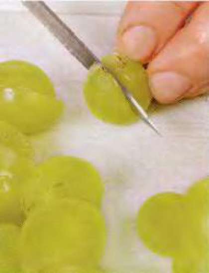 Ягоды винограда удалить с кисти, перебрать и хорошенько промыть. Порезать каждую ягоду на две половинки, удалить  косточки.