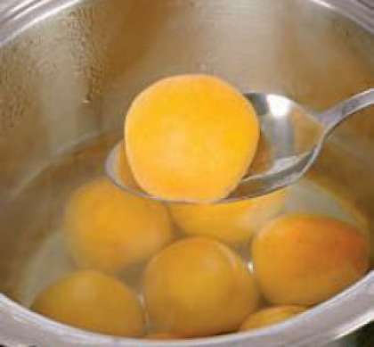 Нарезать абрикосы пополам, косточку нужно удалить. В миску налить  небольшое количество воды, засыпать оставшийся  сахар и довести до кипения. Уменьшить  температуру, поместить абрикосы и готовить в течении 2 мин. Выложить половинки абрикосов поверх молочного желе.